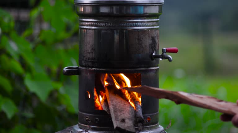 A man stoking the flames of the samovar and adding firewood to the samovar