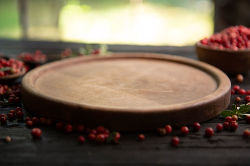 Empty circle wooden board and cranberry on rustic table