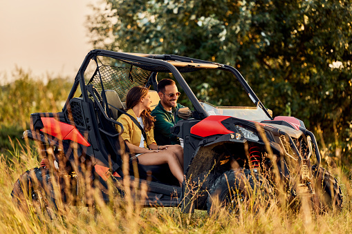 A smiling man and woman sitting on a rented quad bike and having an adventure off-road.