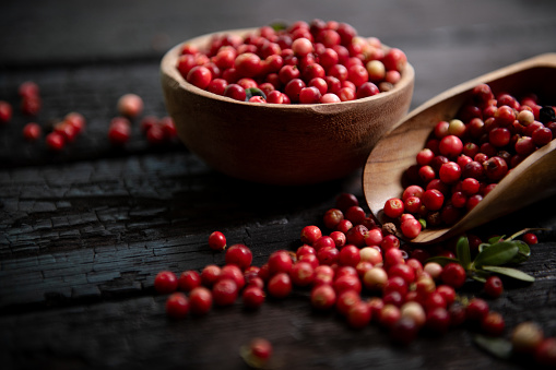Fresh raw cranberry in wooden bowl on rustic table