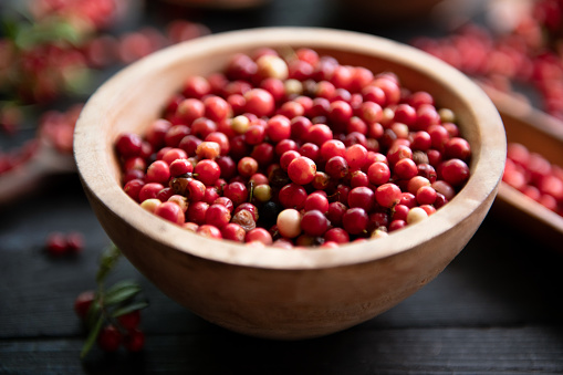 Fresh raw cranberry in wooden bowl on rustic black table