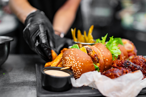 chef cooking fast food set on plate. burger, chicken wings on kitchen