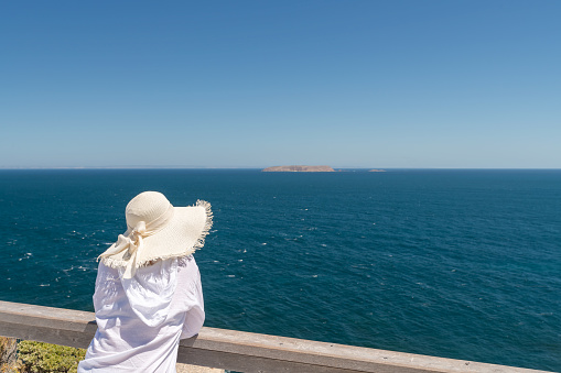 Woman wearing white shirt with white hat looking into the ocean at Cape Spencer, Yorke Peninsula, South Australia