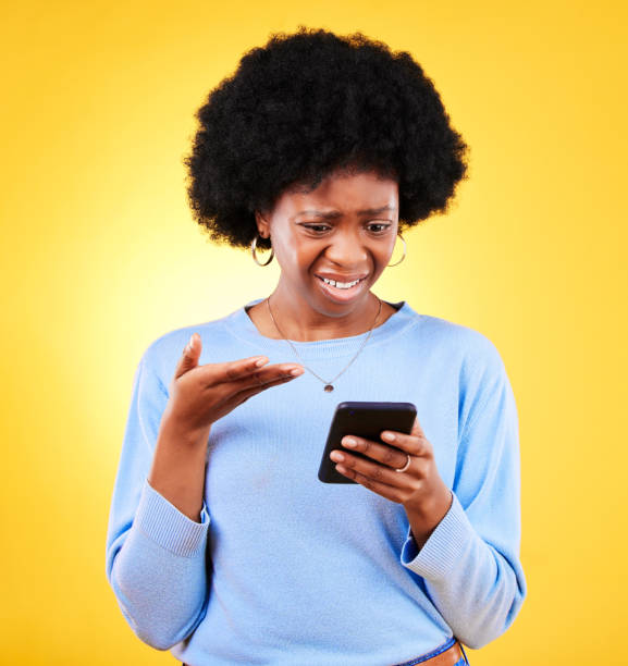 istock Frustrated, fraud and woman with phone scam and shock from problem and tech in studio. Stress, mobile error and confused from phishing, hacking and ecommerce spam with anxiety and yellow background 1682203127