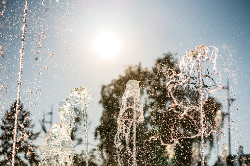 Water fountain drops glistening in the sun in a park.