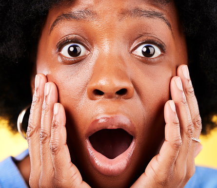 Scared, shock and surprised woman in studio for fear, mental health or zoom. Portrait of African person on yellow background mouth open, hands on face or frightened by phobia, gossip news or horror