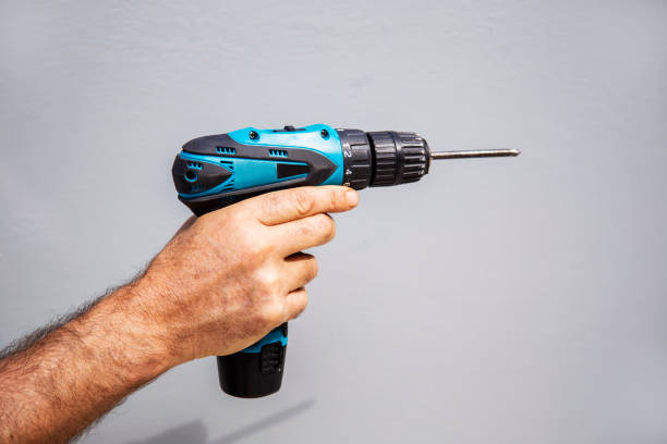 istock Carpenter holding a cordless screwdriver to drill against grey background isolated 1682220718