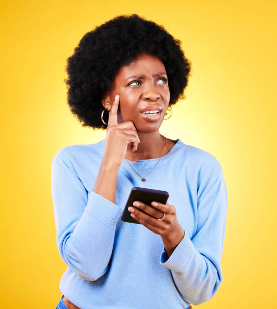 istock Confused, thinking and black woman with mobile for a chat, communication or an app. Website, contact and an African girl with doubt about an online message or web notification on a yellow background 1682226630