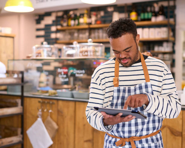 istock Man With Down Syndrome Working In Food Shop Using Digital Tablet 1682238778