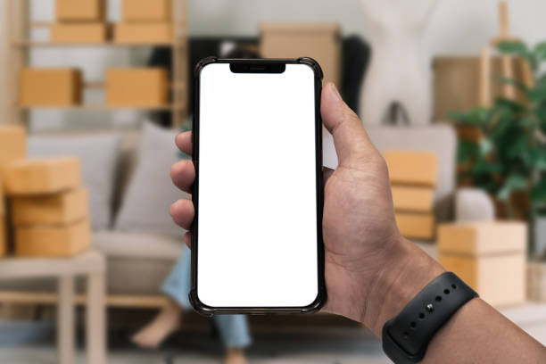 istock Business - technology and office concept - Hand holding mobile phone with blank screen in office. 1682239912