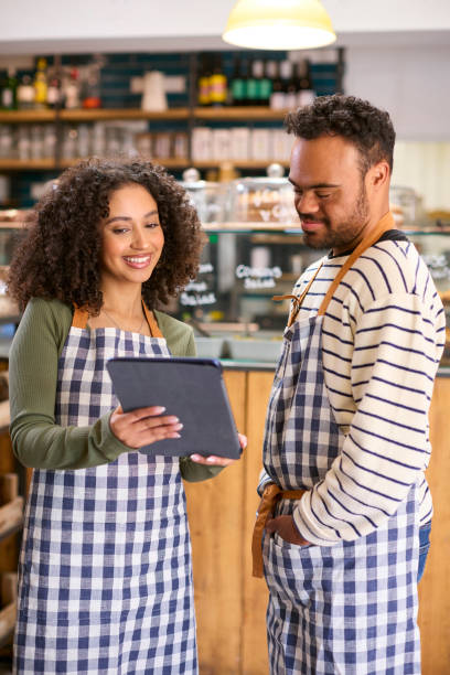 istock Woman Using Digital Tablet Working In Food Shop Training Man With Down Syndrome 1682243247