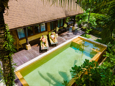 house with a swimming pool, a modern pool villa, luxury villa in Thailand, a couple of men and woman on a luxury vacation in Thailand at a 5 star resort relaxing in the swimming pool during holiday