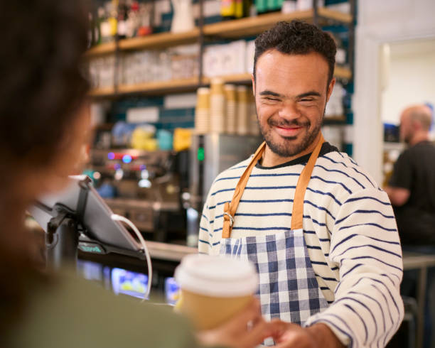 istock Man With Down Syndrome Serving Female Customer At Coffee Shop Checkout 1682257527
