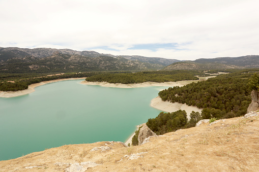 Green lake in the desert of Tabernac in Andalucia, Spain, with trees and mountains in the background