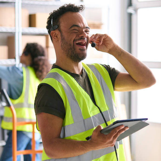 istock Man With Down Syndrome Working In Warehouse Wearing Headset Using Digital Tablet 1682265544