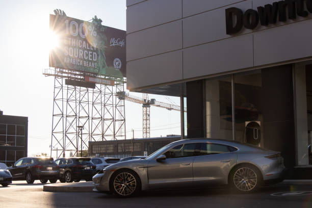 A silver Porsche Taycan EV out front of a Porsche dealer. stock photo