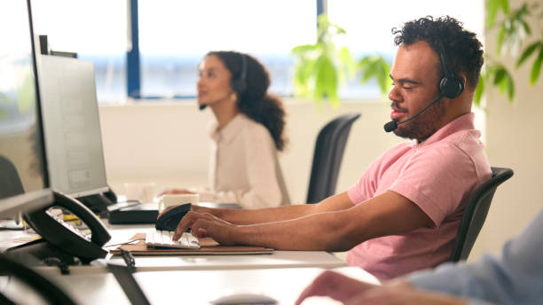 istock Man With Down Syndrome Wearing Headset Working In Office Call Centre Team 1682277671