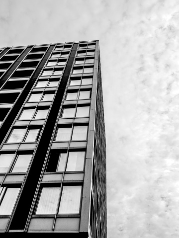Black and vhite low angle view of a building with many windows, lfet lower part of the image.