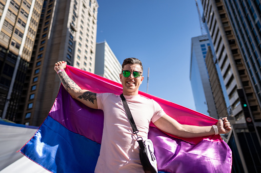 Portrait of a young man holding bisexual flag at the Gay Parade