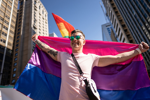 Young man holding bisexual flag at the Gay Parade