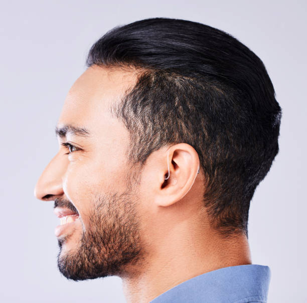 istock Man, hearing aid and studio profile for ear, wellness and smile for solution by white background. Happy patient, audio tech and hearing for person with disability with smile, sound implant and health 1682298286