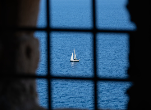 Sailing boat at the open sea high angle view through window bars