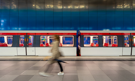 Germany, Hamburg, August 17, 2023 -Blurred motion of person at subway station against subway train Hamburg Hafencity