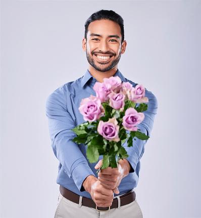 Roses, portrait and happy man in studio with thank you, present or offer on grey background space. Face, flowers and Japanese male model with floral, bouquet or gesture of kindness, love or romance