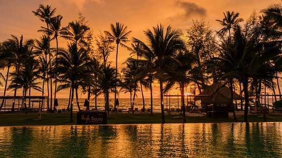 sunset at a tropical swimming pool with palm trees at the island of Koh Kood Thailand, pool during sunset on the beach at a luxury hotel resort