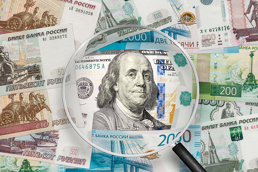 American dollar  and Russian ruble banknotes. View through magnifying glass