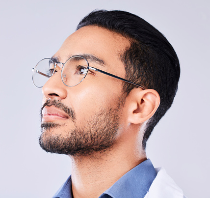 Thinking, glasses and a man or doctor on a studio background for healthcare or medical vision. Medicine, idea and an Asian nurse or surgeon with a service solution or optometry on a backdrop