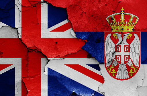 flags of UK and Serbia painted on cracked wall