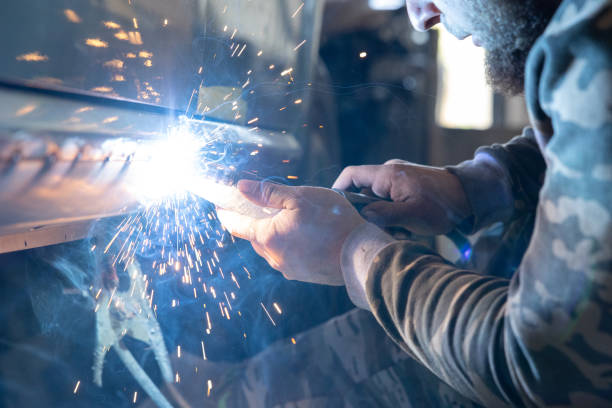 the professional auto mechanic uses a welding machine to repair a car. - car bodywork flash imagens e fotografias de stock