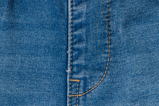 blue denim fabric made of cotton, details of a piece of clothing sewn from blue denim