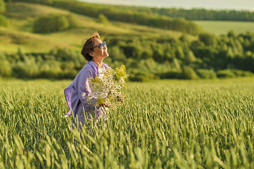 Joyous senior woman exploring a beautiful meadow, highlighting the appeal of nature tourism for seniors.