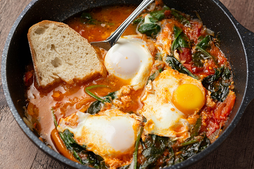 Shakshuka served in cast iron Frying Pan. Eggs in Spicy Tomato Pepper Sauce.