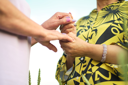 Timeless Support: Against the vibrant hues of a nature-filled background, two elderly women holding hands show that support and friendship are ageless concepts