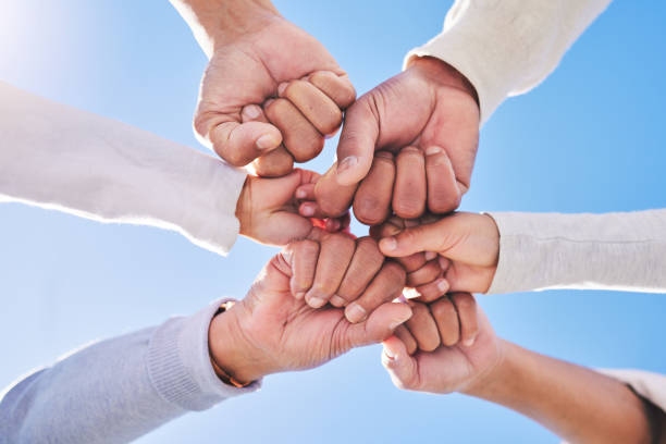 istock Hands in circle, blue sky and diversity for community in collaboration for global support and success. Teamwork, fist and bottom view of group of friends with positive vision, trust and love outdoors 1682465195