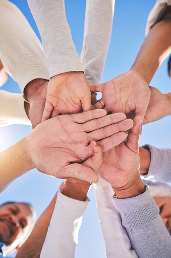 Stack of hands, blue sky and diversity of people for community in collaboration for global support. Teamwork, palm and low angle of group of friends with positive vision, trust and love outdoors.