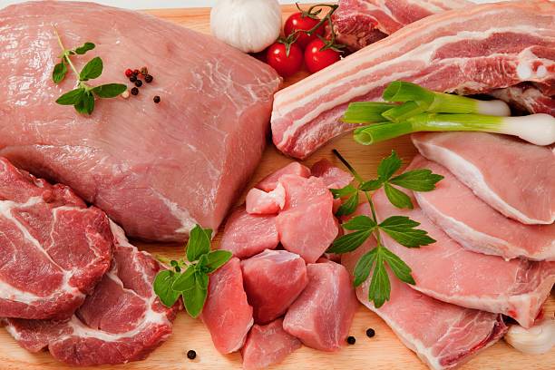 Raw cuts of pork meat on a wooden chopping board stock photo