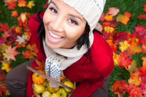 Smiling woman sitting on autumn leaves
