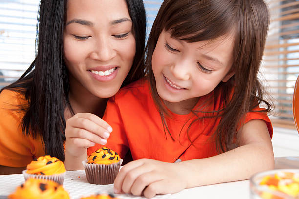Mother and daughter baking halloween cupcakes Mother and daughter celebrating halloween halloween cupcake stock pictures, royalty-free photos & images