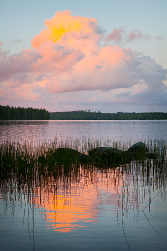 Cumulus clouds above Lake Kuuhankavesi located in Hankasalmi, Finland. The setting sun colors the clouds orange and yellow.