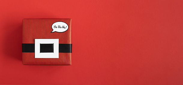 Red Santa gift box with black belt and speech bubble ho-ho-ho on red background. Space for yout text.
