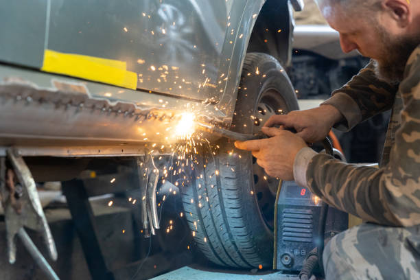 the professional auto mechanic uses a welding machine to repair a car. - car bodywork flash imagens e fotografias de stock