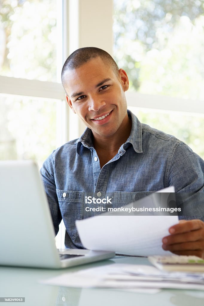 Giovane uomo utilizzando un computer portatile a casa - Foto stock royalty-free di Abbigliamento casual
