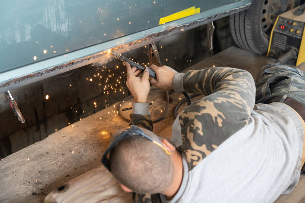 the professional auto mechanic uses a welding machine to repair a car. - car bodywork flash imagens e fotografias de stock