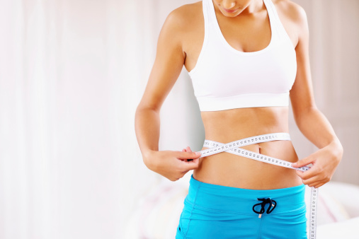 Portrait of young woman measuring her waistline