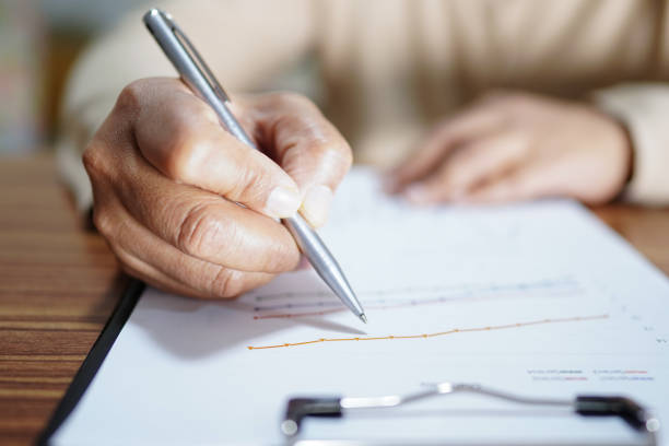 istock Asian woman hand using pen writing on paper while sitting at the table.. 1682501579