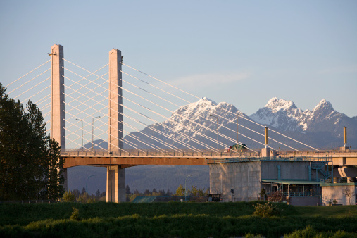 Evening shot of bridge with Golden Ears Mountain Peaks and Provincial Park in background. The Golden Ears Bridge is a new toll bridge that links Pitt Meadows And Maple Ridge British Columbia to Langley,Surrey and beyond.  There is an electronic tolling system that allows drivers to pay without stopping. The bridge crosses the Fraser River. *Golden Ears is one of the largest Provencial Parks in British Columbia 